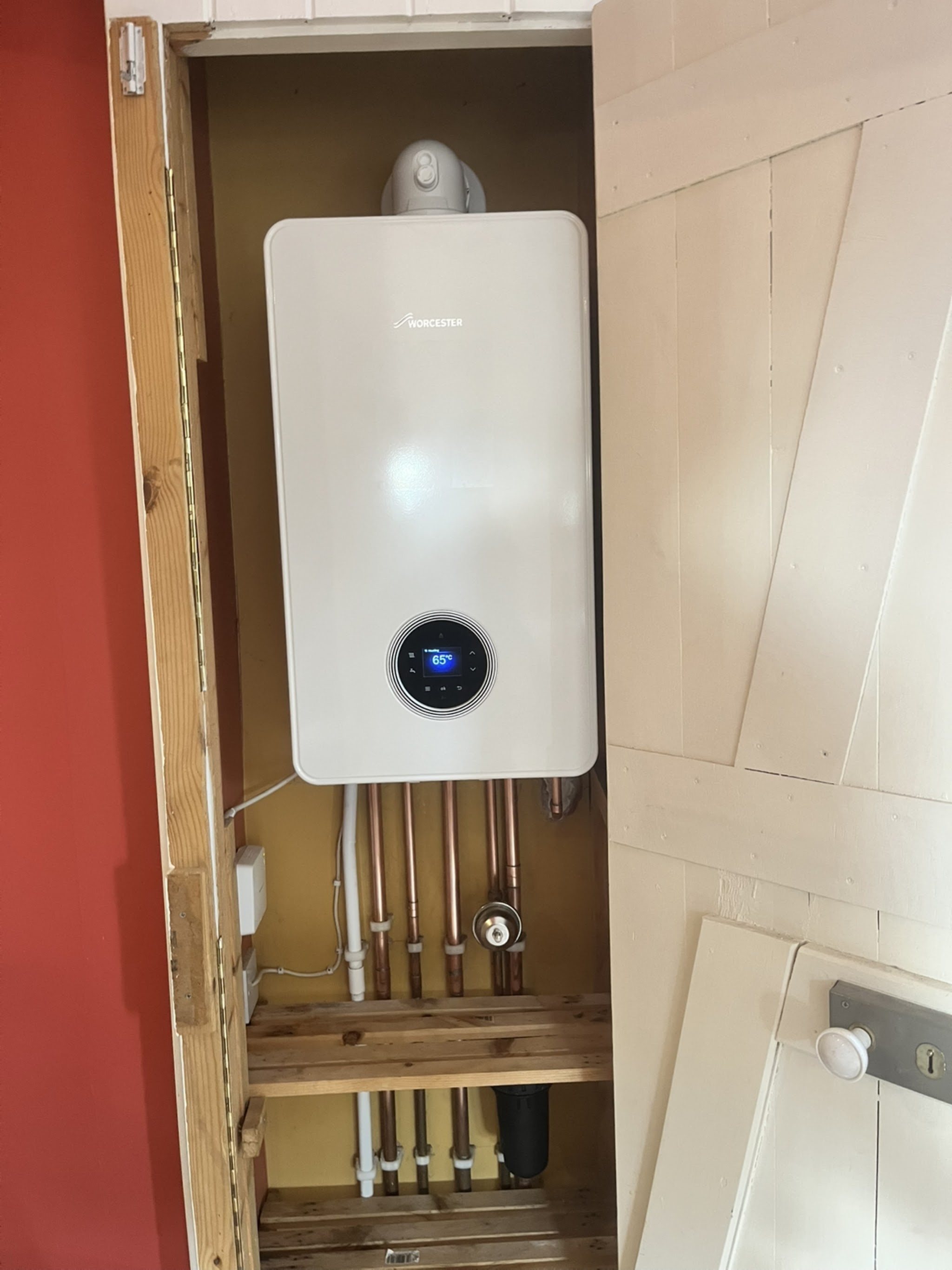 A new white combi boiler we fitted inside a timber cupboard, with neat pipework below