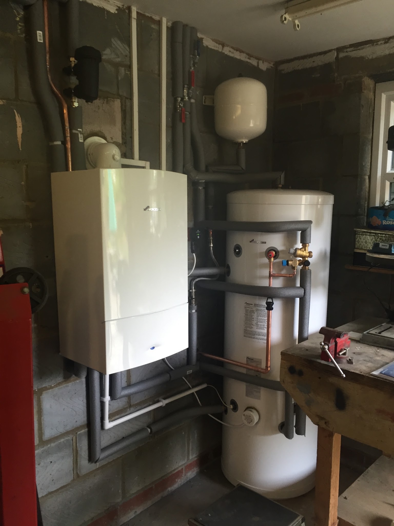 A wall-hung boiler beside an unvented cylinder in a utility room