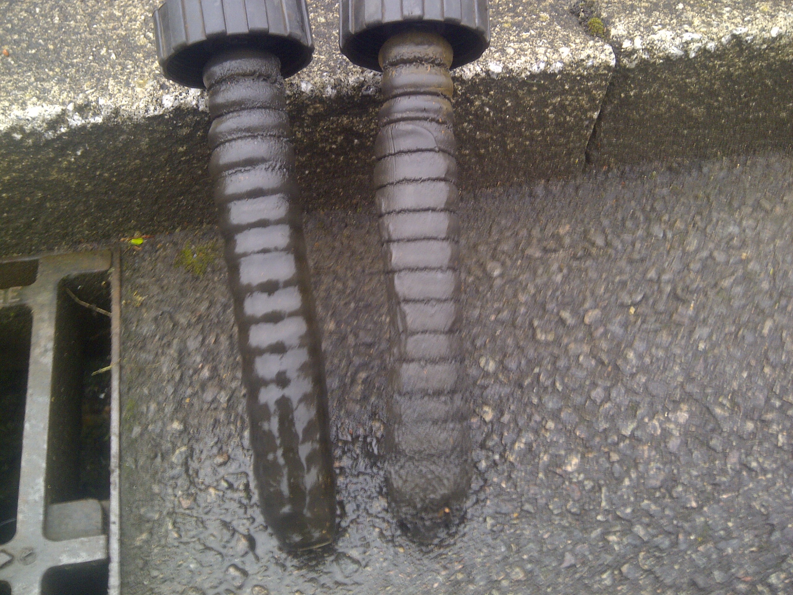 Two magnetic filter rods caked in black sludge pulled out of a heating system during a power flush
